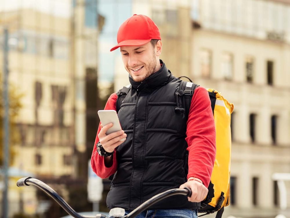 delivery-guy-with-phone-sitting-on-bicycle-using-a-X9U9AJX.jpg